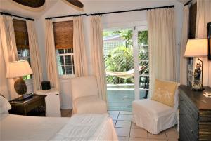 a bedroom with a bed and a chair and a window at Simonton Court Historic Inn & Cottages in Key West +209 photos