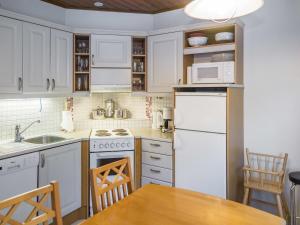 a kitchen with white appliances and a wooden table at Holiday Home Alppitalo punatähti 7 apt 4 by Interhome in Tahkovuori