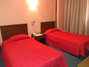 2 camas en una habitación de hotel con colchas rojas en Hotel Maria Victoria Xalapa en Xalapa
