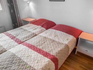 a bed with a red and white quilt on it at Holiday Home Alppitalo punatähti 7 apt 4 by Interhome in Tahkovuori