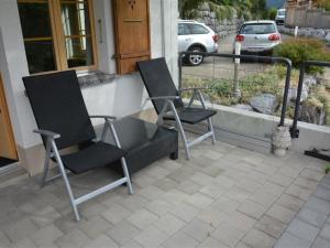 2 chaises assises sur la terrasse couverte d'une maison dans l'établissement Apartment Bijou Eggetli by Interhome, à Zweisimmen