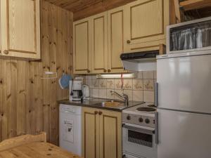 une cuisine avec des armoires en bois et un réfrigérateur blanc dans l'établissement Holiday Home Ylläskarpalo 1 päätyhuoneisto by Interhome, à Äkäslompolo