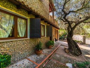 a stone house with a tree next to it at Holiday Home Cala Tuent by Interhome in Cala Tuent