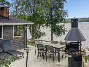 een patio met een tafel en stoelen en een grill bij Holiday Home Rahkola by Interhome in Sipsiö
