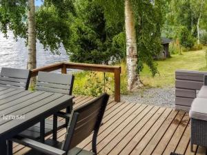 een houten terras met 2 stoelen en een tafel bij Holiday Home Rahkola by Interhome in Sipsiö
