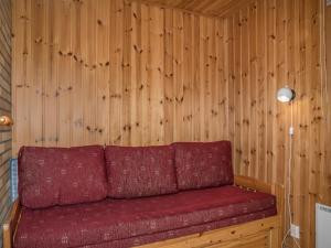 - un canapé rouge dans une chambre dotée d'un mur en bois dans l'établissement Holiday Home Ylläskarpalo 2 keskimmäinen by Interhome, à Äkäslompolo 10 autres photos