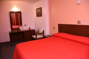 Habitación de hotel con cama roja y escritorio. en Hotel Maria Victoria Xalapa en Xalapa