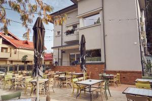 an outdoor patio with tables and chairs and umbrellas at Villa Piazzetta in Bacău
