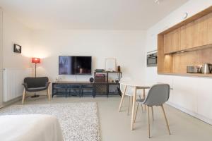 ein Wohnzimmer mit einem Tisch und Stühlen sowie einem TV in der Unterkunft Mini loft with terrace in Brüssel