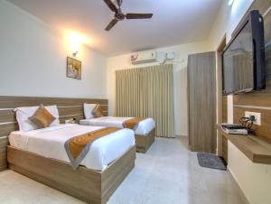Una habitación de hotel con dos camas y un televisor de pantalla plana. en Sunshine Suites Grand Deluxe, en Bangalore 8 fotos más