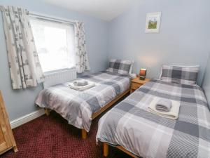 two twin beds in a room with a window at The Stables in Penzance