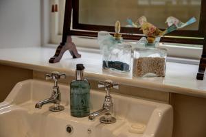 a bathroom sink with two glass bottles on a counter at Low Raisgill B&B in Buckden