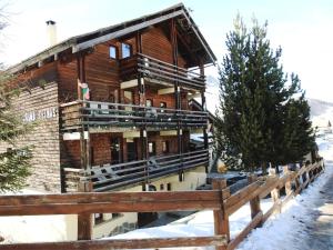 un edificio de madera con una valla en la nieve en Le Grand Tetras, en Saint-Véran