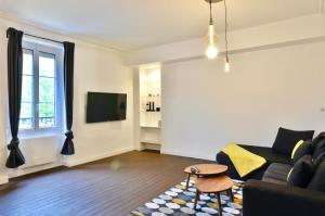 a living room with a couch and a tv at Appart Hotel NuitéeJour Le Mans Centre Jaurès in Le Mans