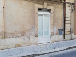 a white door on the side of a building at Triskelion in Scicli