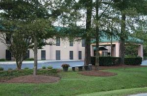 a large white building with trees in front of it at Moncks Corner Inn in Moncks Corner