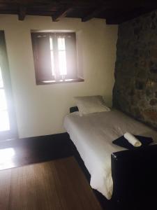 a bedroom with a bed and a stone wall at Flor de Pomar in Corao