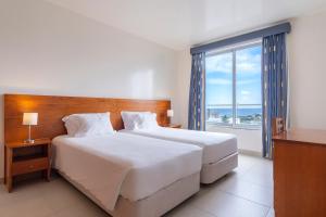 a bedroom with a large bed and a large window at Acorsonho Apartamentos Turisticos in Capelas