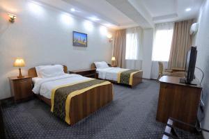 a hotel room with two beds and a flat screen tv at VIARDO Hotel in Tashkent