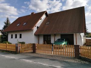 a white house with a fence and a green car at Ferienwohnung Nordlicht in Großdubrau