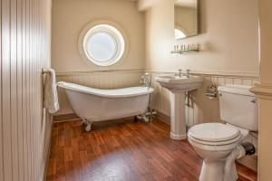a bathroom with a tub and a toilet and a sink at Botany Bay Hotel in Broadstairs +37 photos