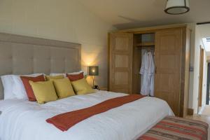 um quarto com uma grande cama branca com almofadas amarelas e vermelhas em Vineyard Barn Room em Stroud