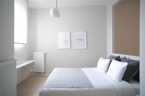 ein weißes Schlafzimmer mit einem Bett mit weißer Bettwäsche und Kissen in der Unterkunft Brussels city flats in Brüssel