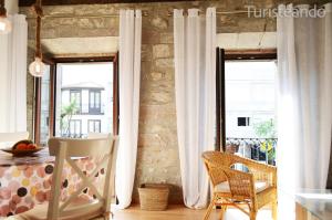 um quarto com duas janelas e uma mesa e cadeiras em Apartamento Llerandi 1C - Ideal para dos personas em San Vicente de la Barquera