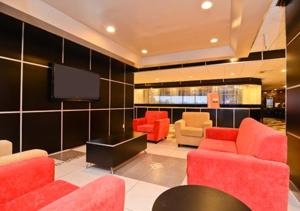 a living room with red chairs and a flat screen tv at Travelodge by Wyndham Absecon Atlantic City in Absecon