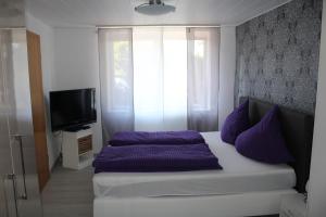 um quarto com uma cama com almofadas roxas e uma janela em Ferienhaus Milena em Lieser