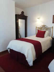 Un dormitorio con una cama grande con una almohada roja. en El Hotel de Su Merced, en Sucre