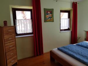 Schlafzimmer mit roten Vorhängen, einem Bett und einer Kommode in der Unterkunft Ferienhaus Habitat Wonnegau in Flörsheim-Dalsheim