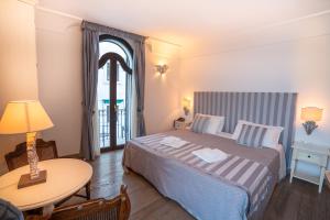 a bedroom with a bed and a table and a window at Covo dei Saraceni in Polignano a Mare