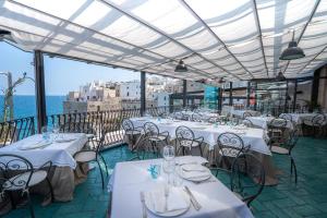 a restaurant with white tables and chairs on a balcony at Covo dei Saraceni in Polignano a Mare