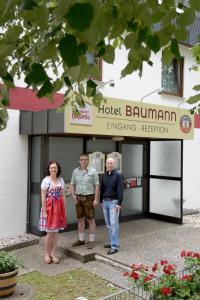 three people standing in front of a hotel building at Hotel - Restaurant Baumann in Freiberg am Neckar