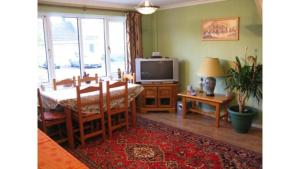 a dining room with a table and a television at Camelot Retreat - Tor View in Glastonbury