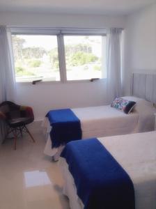 a hotel room with two beds and a window at Depto 203 Edificio Bikini Beach, Manantiales in Punta del Este