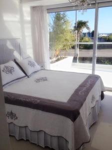 a bedroom with a large bed with a large window at Depto 203 Edificio Bikini Beach, Manantiales in Punta del Este