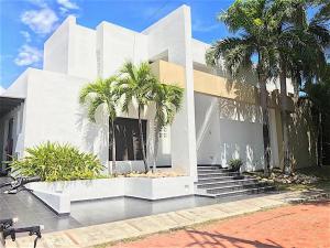 a white building with palm trees in front of it at Casa HESTIA Condominio Campestre el Peñon Girardot in Girardot