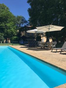 a blue swimming pool with a table and an umbrella at Château de Saint-Girons B&B in Aix-en-Provence