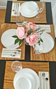 a table with white plates and pink flowers on it at 168 - ExcellentStays - 2 Bedroom Flat in Stanwell