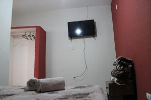 um urso de peluche deitado numa cama com uma televisão na parede em Villa Franco em Águas de São Pedro