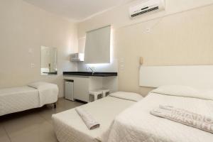 um quarto de hotel com duas camas e uma cozinha em Ilha Norte Apart Hotel em Florianópolis