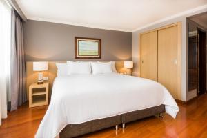 1 dormitorio con 1 cama blanca grande y 2 lámparas en Cosmos 100 Hotel & Centro de Convenciones - Hoteles Cosmos, en Bogotá