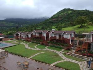 a group of houses with a hill in the background at Green Velvet Resort-Near Pawna Lake in Lonavala