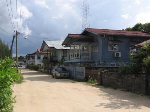a blue house on the side of a dirt road at Cosy home for short stay or a weekend getaway in Paramaribo