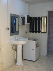 a bathroom with a sink and a small refrigerator at Cosy home for short stay or a weekend getaway in Paramaribo