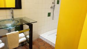 un bagno con lavandino in vetro e doccia di L'ALCOVE HOTEL RESTAURANT a Villematier