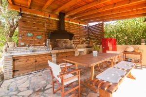 an outdoor kitchen with a wooden table and chairs at Villa Magia in Ipsos