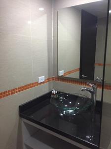 La salle de bains est pourvue d'un lavabo en verre et d'un miroir. dans l'établissement Hotel Garden City Boutique, à Fusagasuga